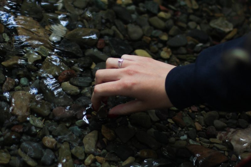 Someone picking up a pebble in a stream