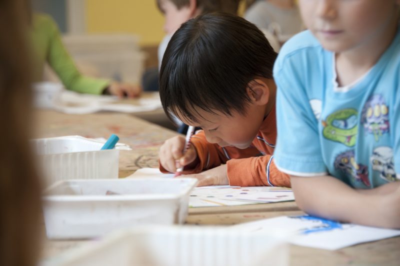 a child colouring at a desk in school