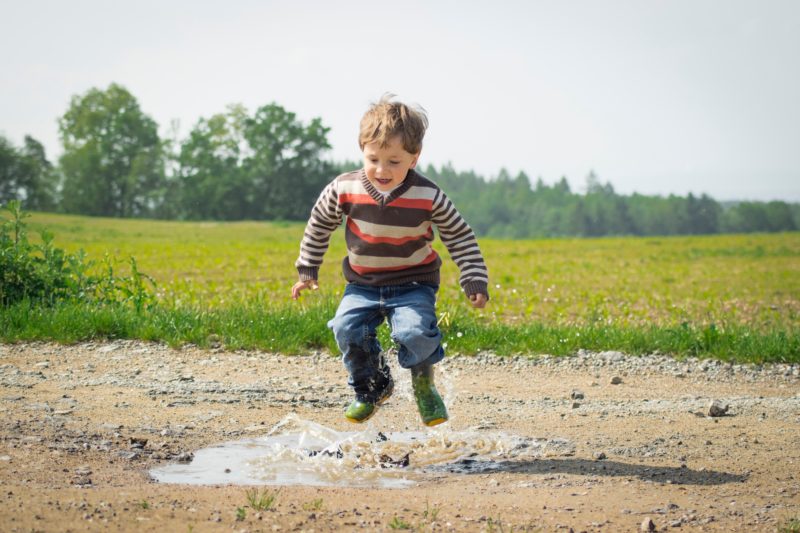 autism diagnosis: a child playing in a puddle in the middle of a green field